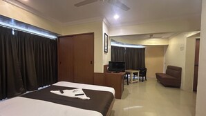Una habitación de hotel con cama, escritorio con televisor, silla y sofá.