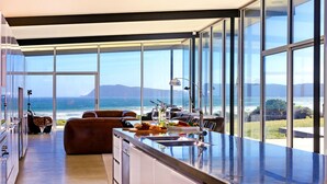 A modern kitchen with large windows overlooking the ocean, a dining area with a view, and a cozy seating area.