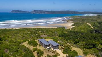 Situated amidst lush greenery, this coastal property offers a tranquil beachside retreat with ocean views and a flat roof.