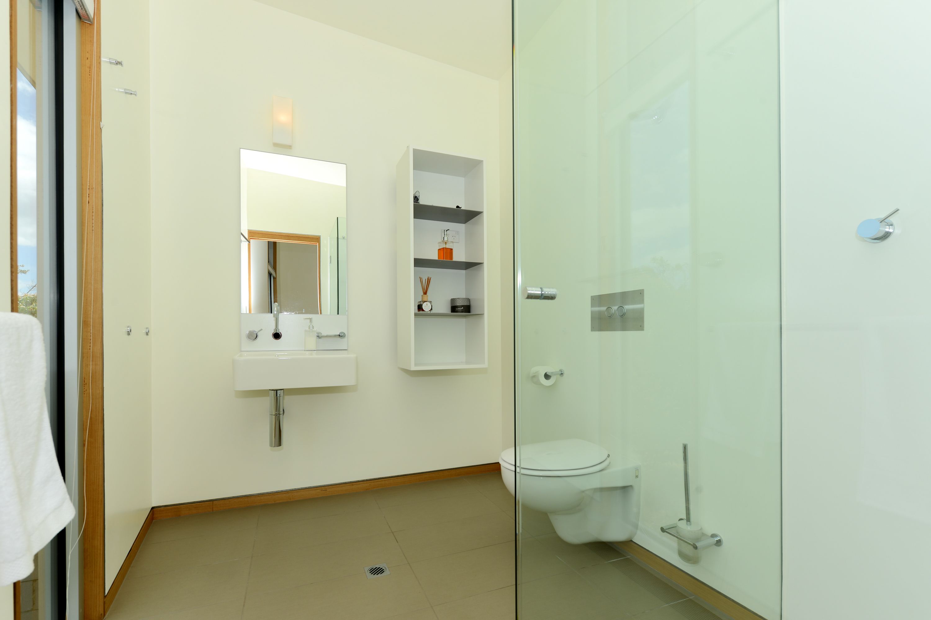 A modern bathroom with a glass shower enclosure, a white sink, and a toilet.
