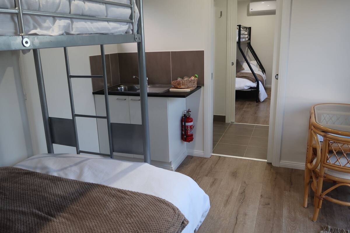 Habitación pequeña con literas, kitchenette y una zona de estar reducida.