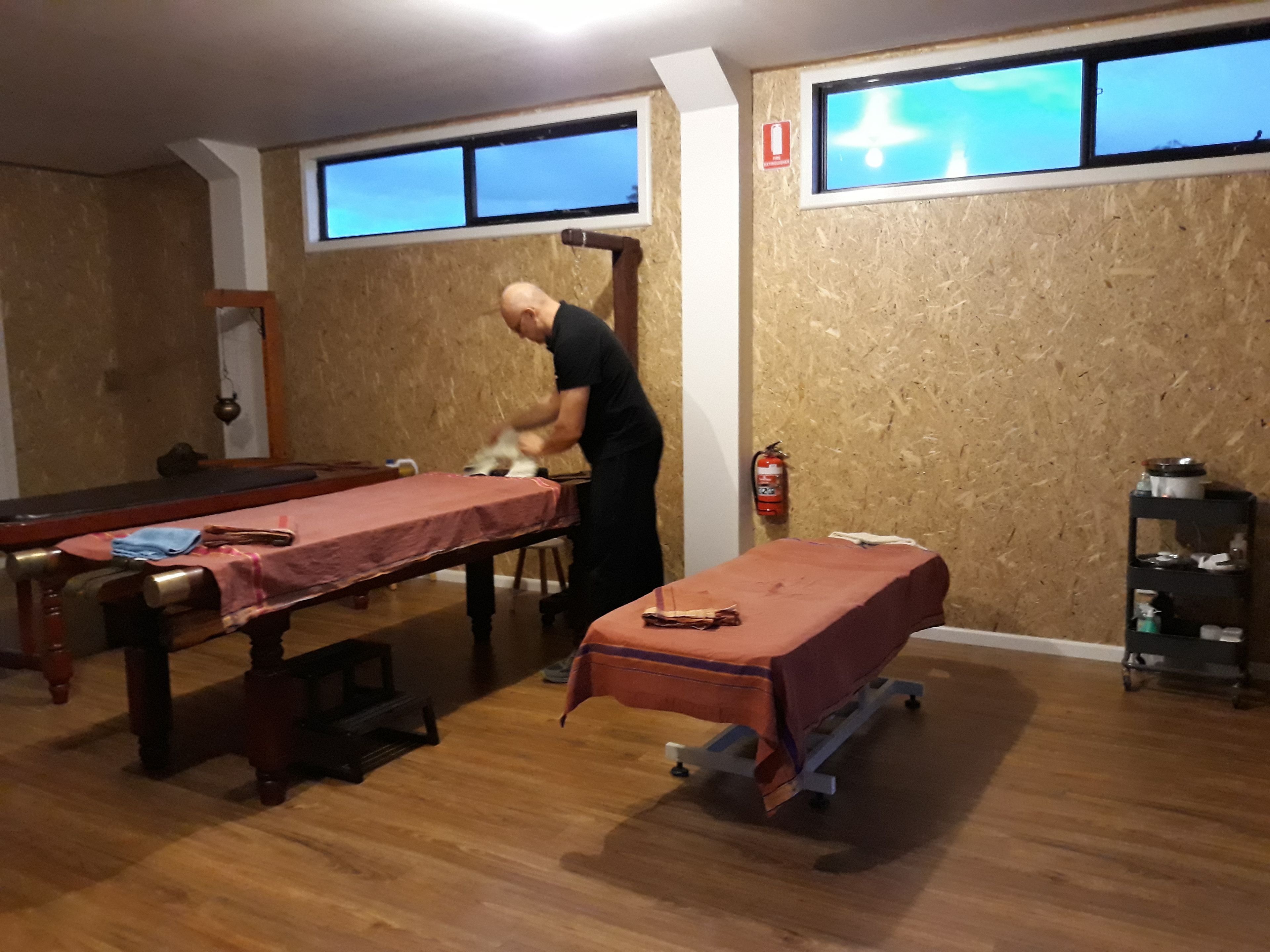 A room with a pool table, a massage table, and a fire extinguisher on the wall.