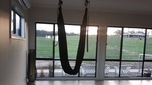 Ein geräumiger Raum mit großem Fenster, einer Hängematte und einer Yogamatte.