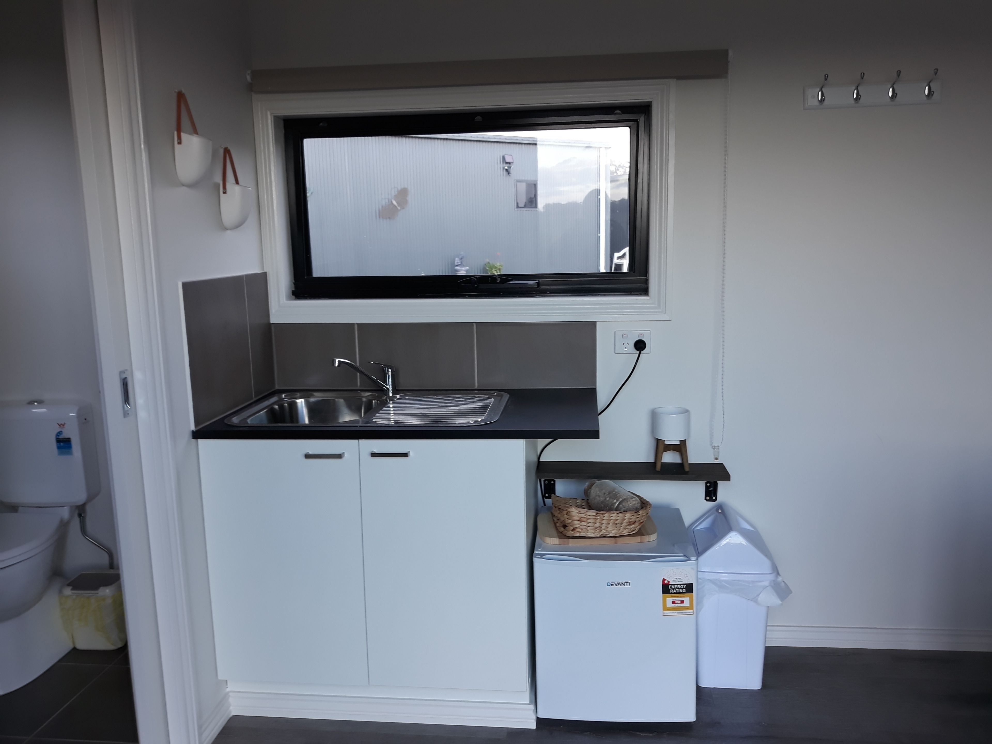 Una cocina compacta con un lavamanos integrado, un refrigerador pequeño y una ventana sobre el lavamanos.