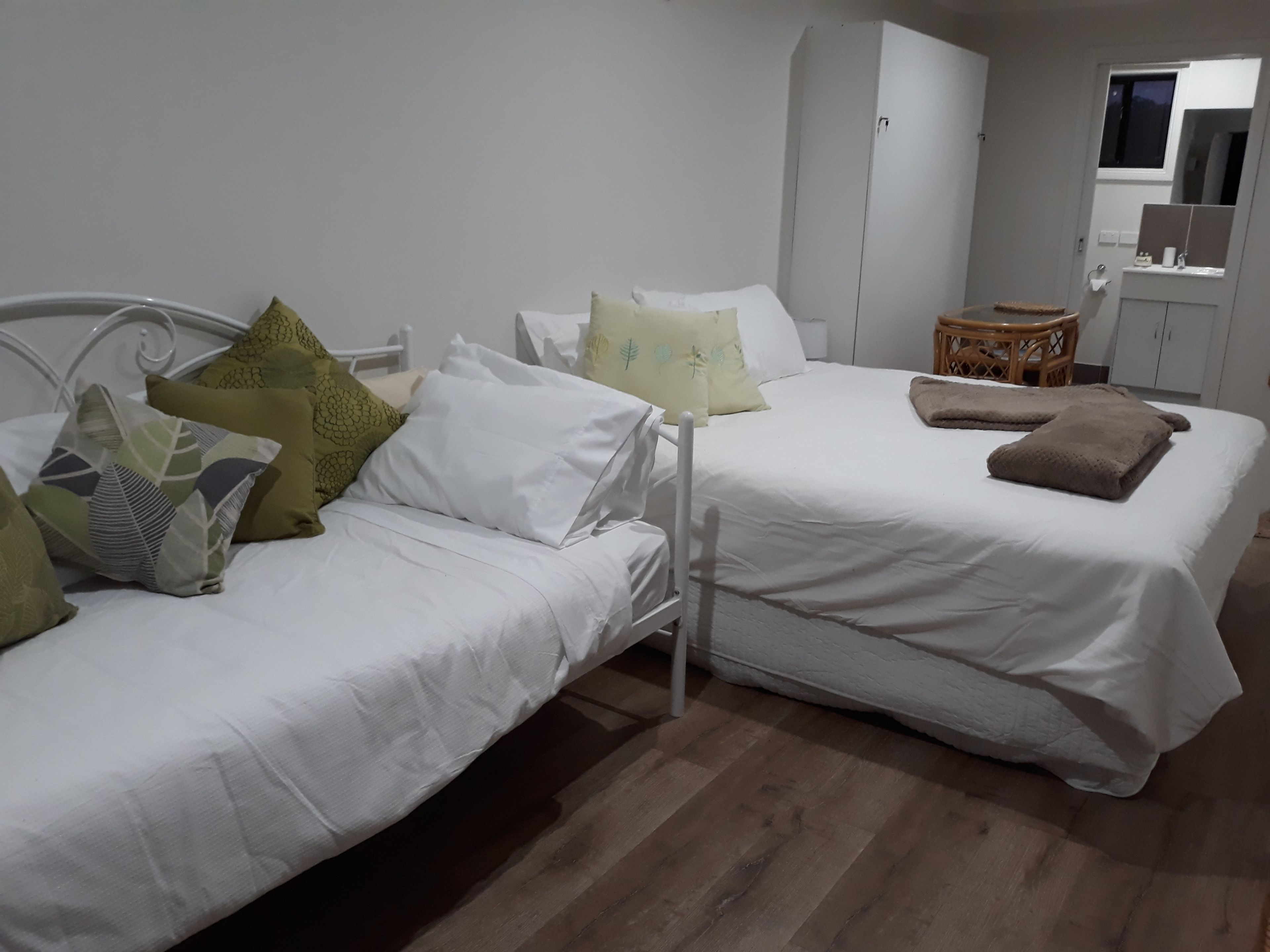 A bedroom with two single beds, white bedding, and a wooden floor.