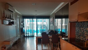 Ett modernt kök med matplats, stora fönster med tunna gardiner och utsikt över en pool.