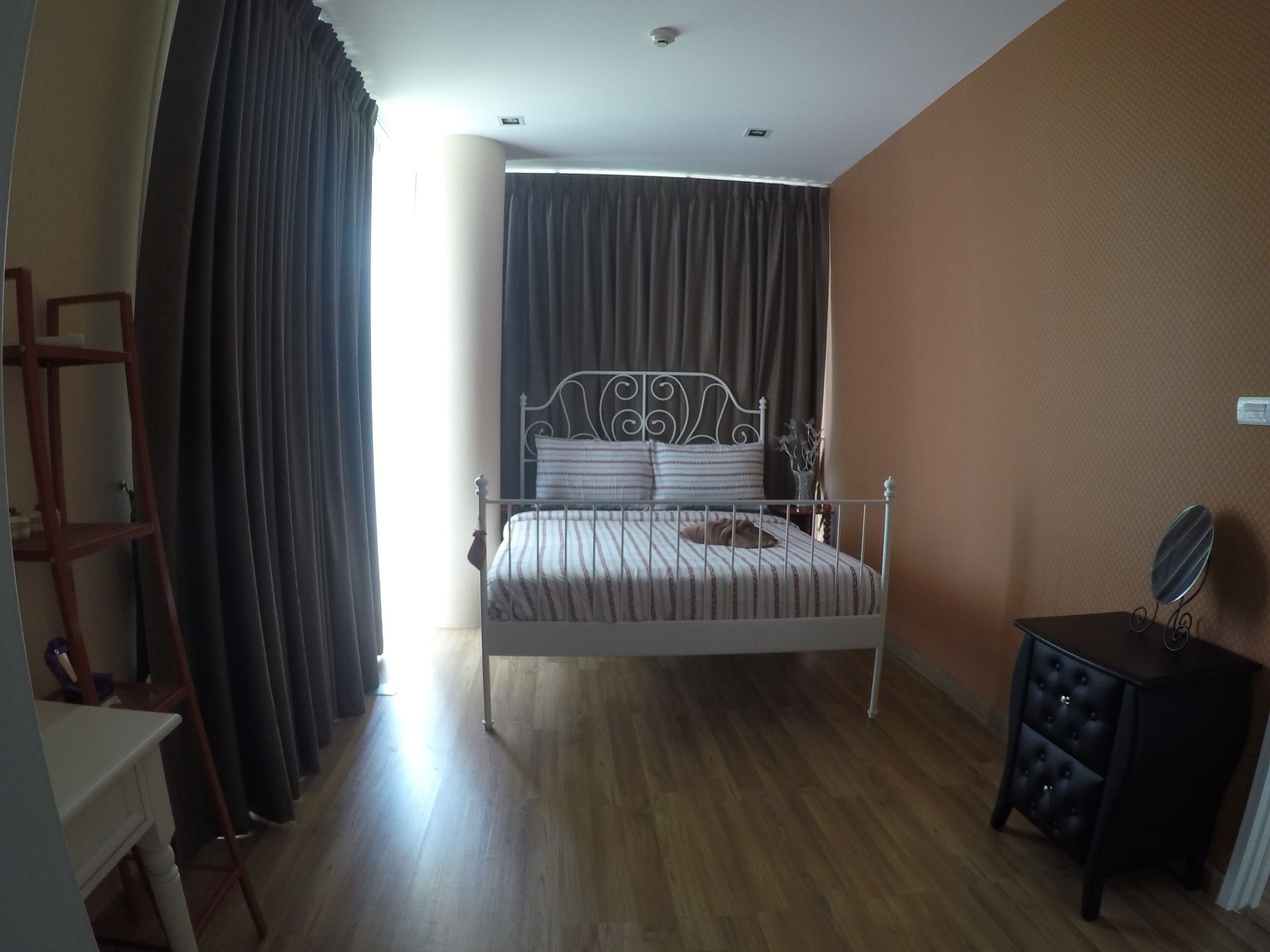 Un dormitorio con cama, cómoda, espejo y ventana con cortinas.