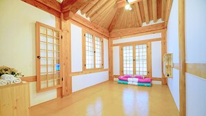 A spacious room with wooden beams, large windows, and a wooden floor. - Lee Ga Hanok (Jeonju)