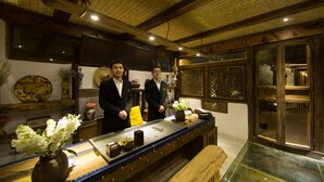 Un intérieur traditionnel avec des poutres en bois, un long comptoir agrémenté de vases et une vitrine.