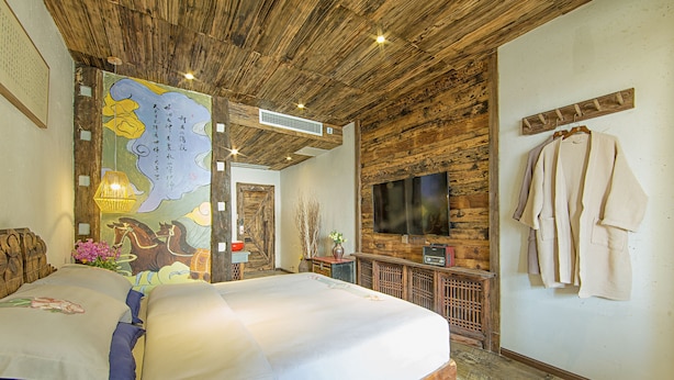 Une chambre avec un grand lit, un plafond en bois, une télévision et un porte-manteau.