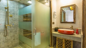 Une salle de bain avec une douche à porte en verre, un meuble-lavabo en bois et un grand miroir.