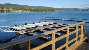 A wooden dock with boats moored at the end, a clear blue sky, and a mountainous landscape in the background. - Furoy Hotel Apartments and Boating (Sorreisa)