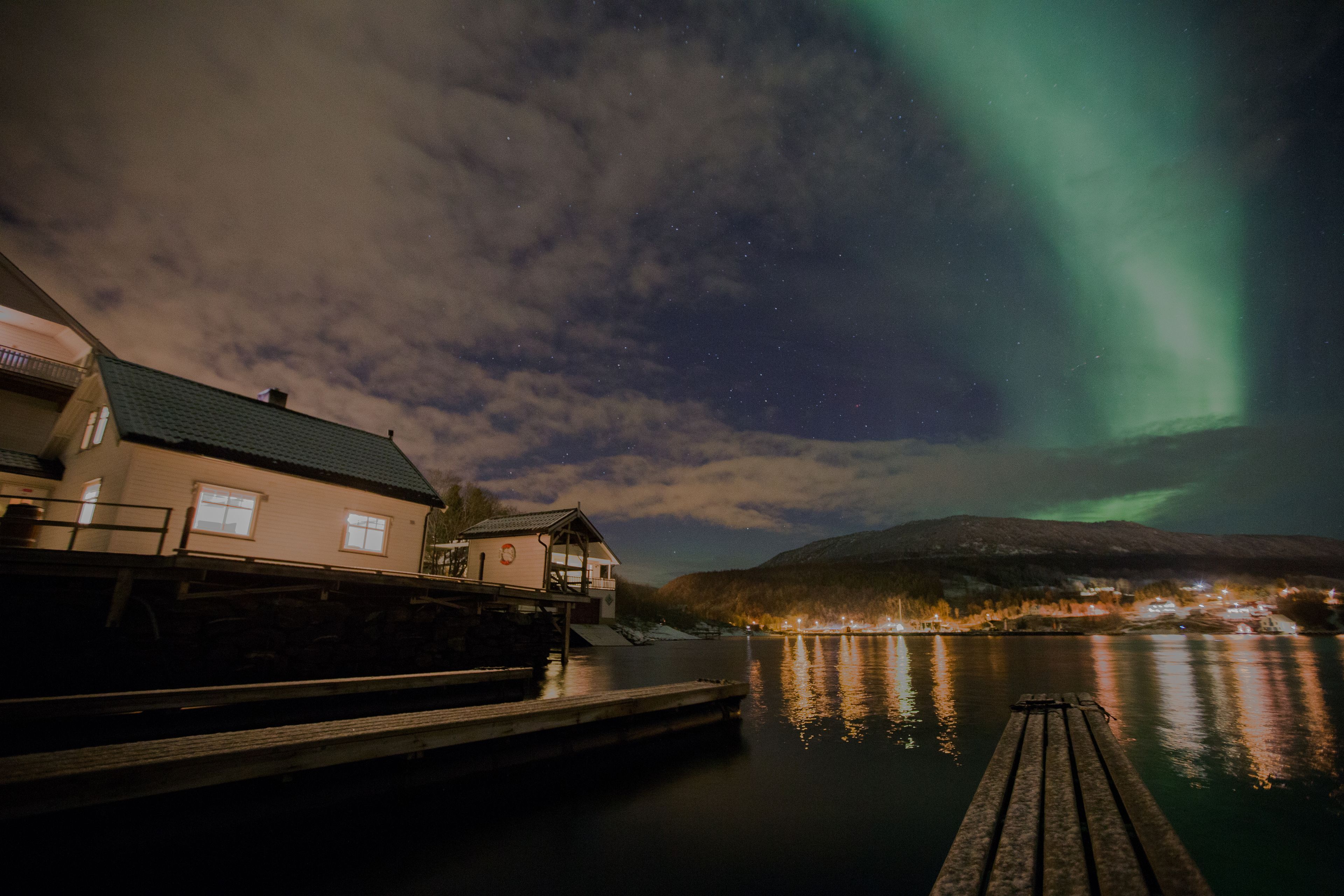 A lakeside view with a dock, a house, and a mountain in the background.