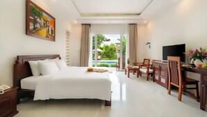 Una habitació d'hotel amb un llit gran, un escriptori amb televisió i vista a un jardí.