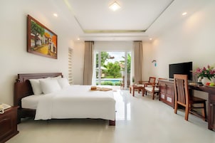 Habitación de hotel con una cama grande, un escritorio con televisión y vista a un jardín.
