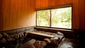 A wooden interior with a stone water feature and a window with a view of trees.