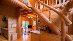 A wooden interior with a staircase, a kitchen area, and a seating space.
