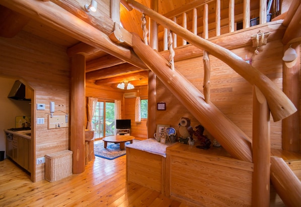 A wooden interior with a staircase, a kitchen area, and a seating space.