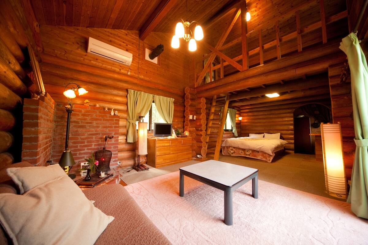 Une chambre confortable dans un chalet en rondins, avec un lit, un bureau et une cheminée.