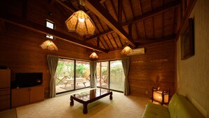 A wooden cabin interior with a sofa, a table, and a television.