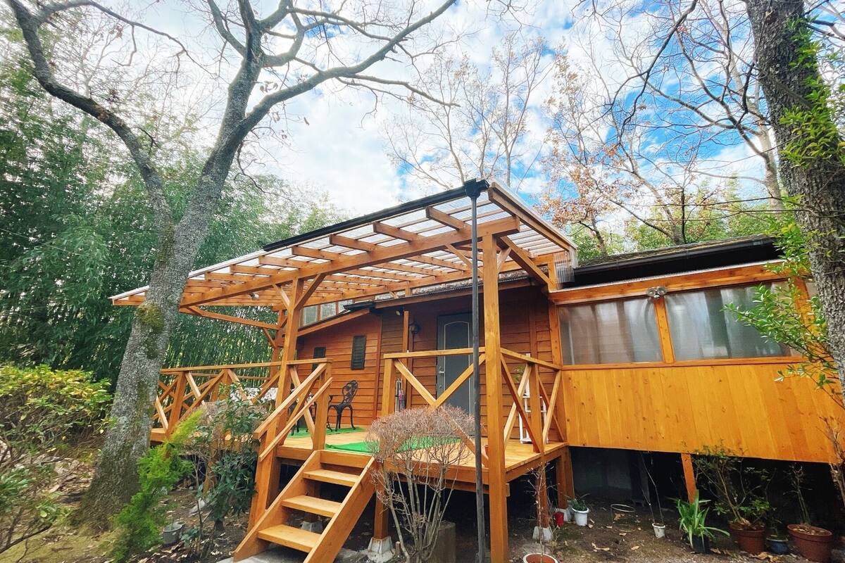 Une cabane en bois dotée d’un porche abrité, d’un escalier et offrant une vue sur la forêt environnante.