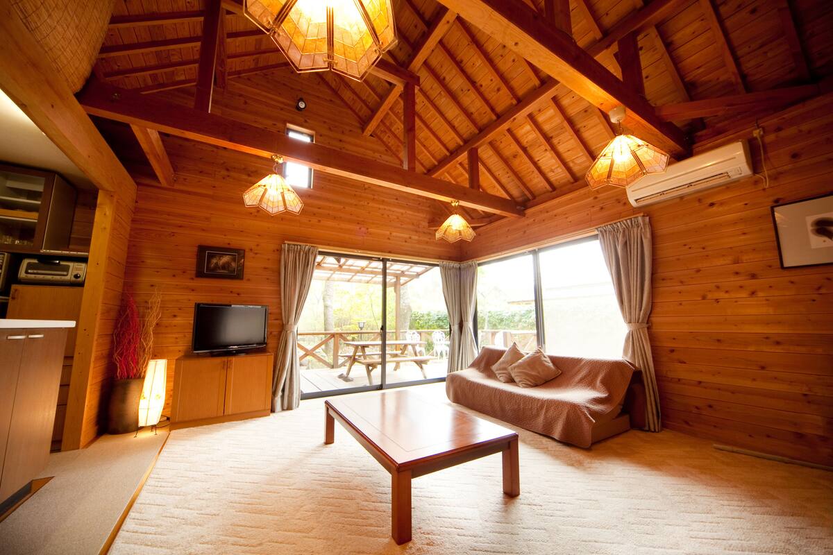 L’intérieur d’un chalet en bois comprend un canapé, une table basse, un téléviseur et un coin repas.