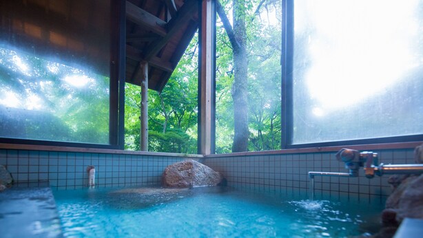 A hot spring with a view of trees through large windows.