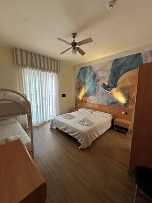 A hotel room with a bed, a ceiling fan, a wooden nightstand, a bedside table, and a large abstract painting on the wall. - Hotel La Maison (Jesolo)