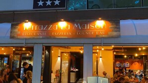 Een restaurant genaamd "Terraza Maison" met een bord waarop staat dat het een restaurant, pizzeria en loungebar biedt.