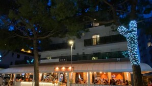 Een restaurant met terras, een overdekt gedeelte en een gebouw met balkons op de achtergrond.