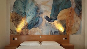 Een hotelkamer met een groot bed, twee nachtkastjes en een grote muurdecoratie.
