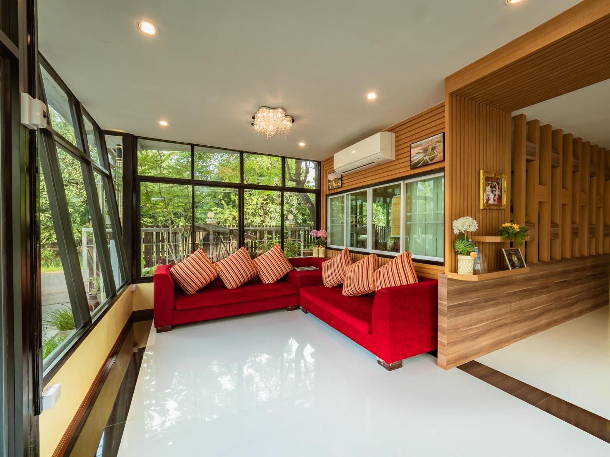 A modern living room with a red sectional sofa, large windows, and a wooden accent wall.