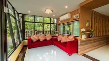 A modern living room with a red sectional sofa, large windows, and a wooden accent wall.