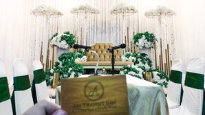 A stage with a microphone stand, a sofa, and decorative floral arrangements. -  AM Transit Inn Kuala Terengganu (Kuala Terengganu)