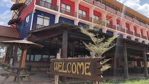 A multi-story building with a colorful facade, a wooden sign reading "WELCOME", and a covered outdoor seating area. -  AM Transit Inn Kuala Terengganu (Kuala Terengganu)