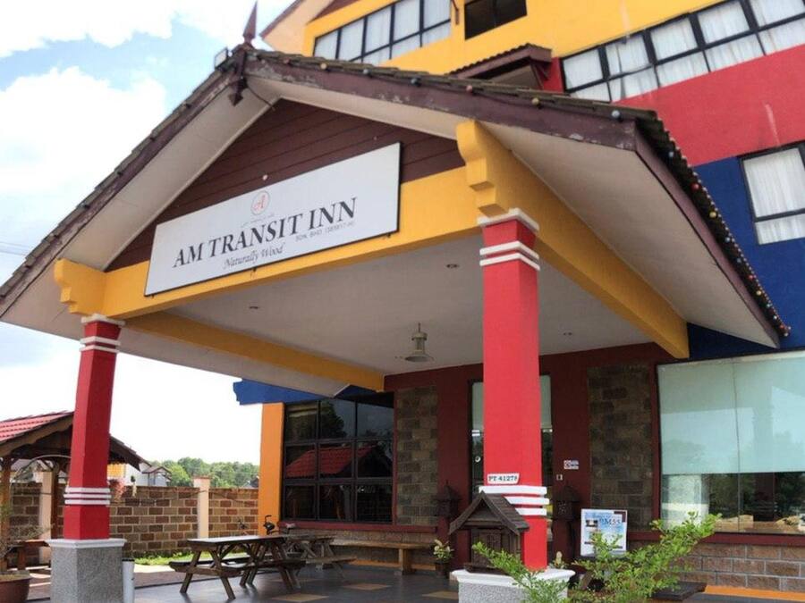 A hotel with a colorful facade, a covered entrance area, and a sign indicating it is the Am Transit Inn.