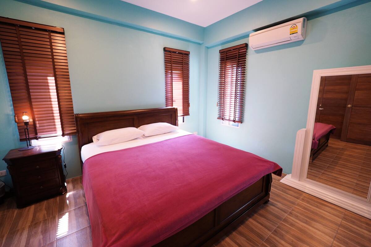 A bedroom with a wooden bed, a nightstand, a dresser, and a wardrobe.