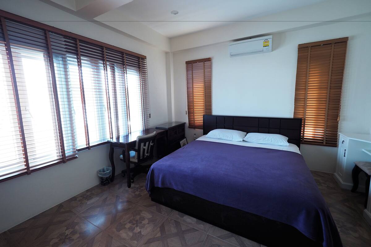 A bedroom with a bed, a desk, and a chair.