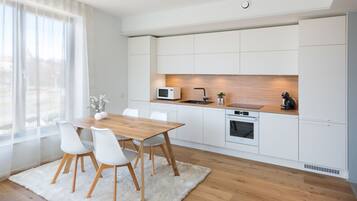 A modern kitchen with white cabinetry, a wooden dining table, and a white rug.