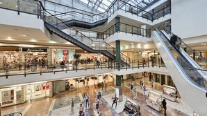 Un centre comercial de diverses plantes connectades per escales mecàniques, amb baranes de vidre i diverses botigues.