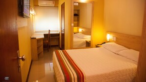 A hotel room with a bed, a desk, a chair, a mirror, and a TV on the wall. - Pousada Costa Doce (Rio Grande)
