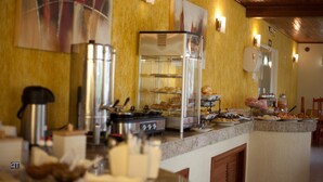 A buffet area with a coffee machine, a refrigerator, and various food items displayed on shelves. - Pousada Costa Doce (Rio Grande)