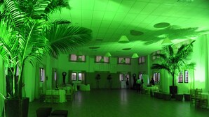 A spacious hall with a high ceiling, large windows, and green ambient lighting.