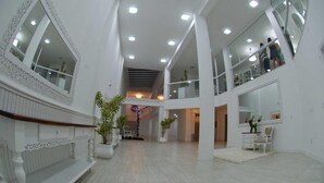 A spacious, multi-level interior with white walls, large windows, and a central staircase.
