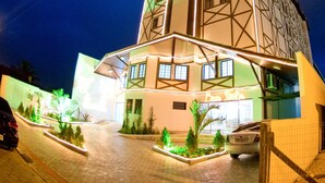 A multi-story building with a unique geometric facade, illuminated by external lighting.