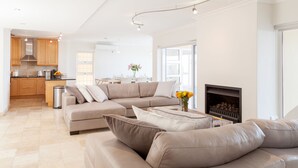 A modern living room with a beige sectional sofa, a coffee table, and a fireplace. - Bay Vista Villa (Cape Town)