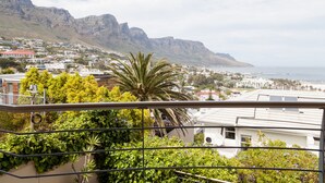A coastal town with a mountain backdrop, featuring residential buildings and lush greenery. - Bay Vista Villa (Cape Town)