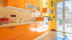 A kitchen with orange cabinets, a white countertop, a red toaster, and a window with a view of the outside.