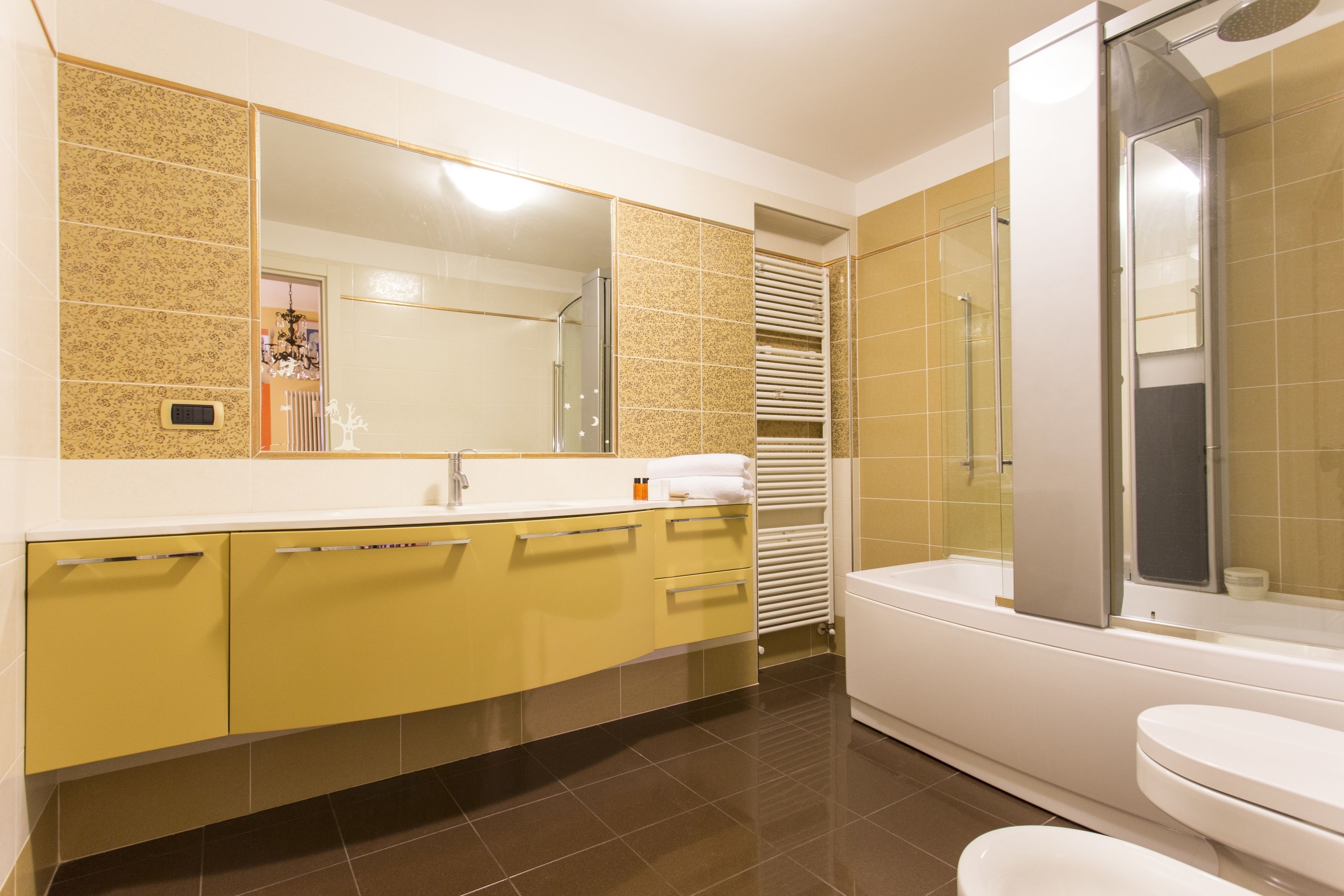 A modern bathroom with a large mirror, a bathtub, and a toilet.