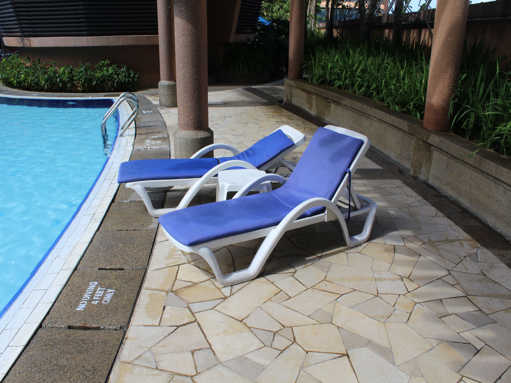 A poolside area with lounge chairs and a tiled floor.